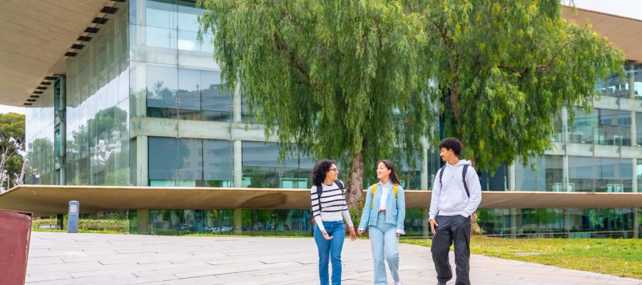 Full length photo with copy space of three multi-ethnic students walking along the university campus