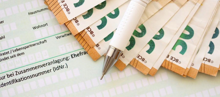 Filling greman tax form process with pen and euro money bills close up. Tax paying period and deadline